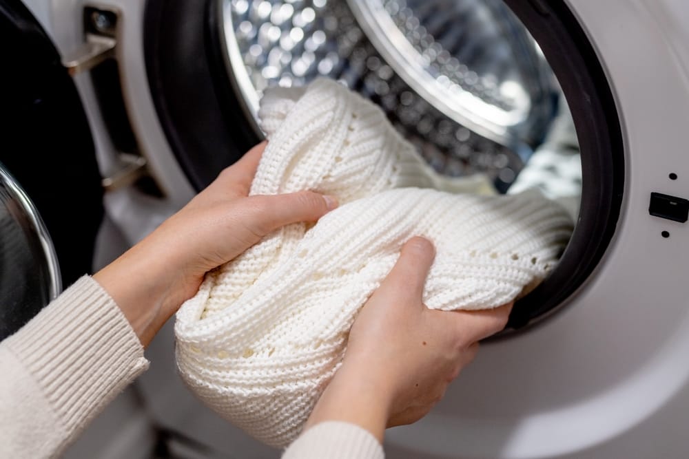 femme mettant des vêtements blancs dans le tambour d'une machine à laver